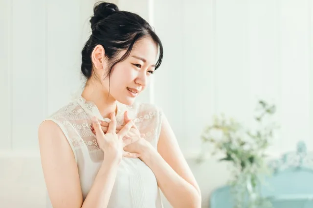 胸の上部を手で押さえる女性