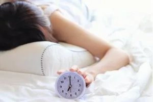 目覚まし時計を止める女性