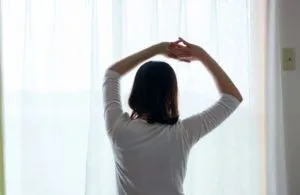 窓際で伸びをする女性