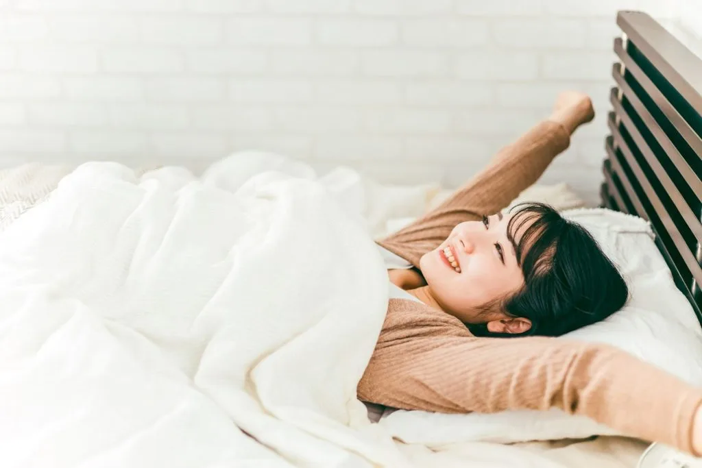 ベッドで手を広げる女性