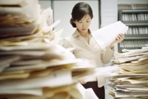 山積みの書類を裁く女性