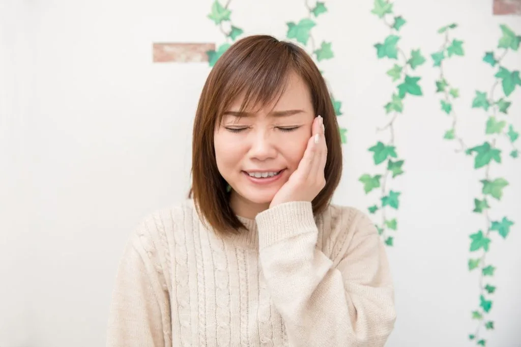 左顎を押さえている女性