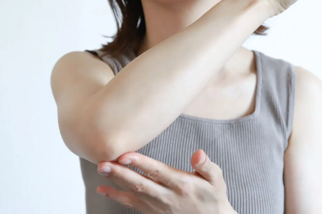 右肘を押さえる女性