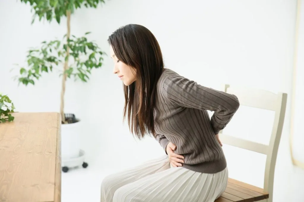 お腹とお尻を手で押さえる女性