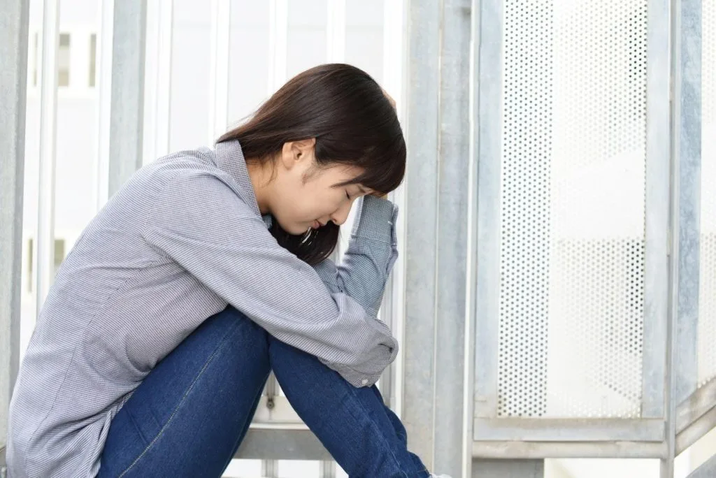 体育座りで悩む女性