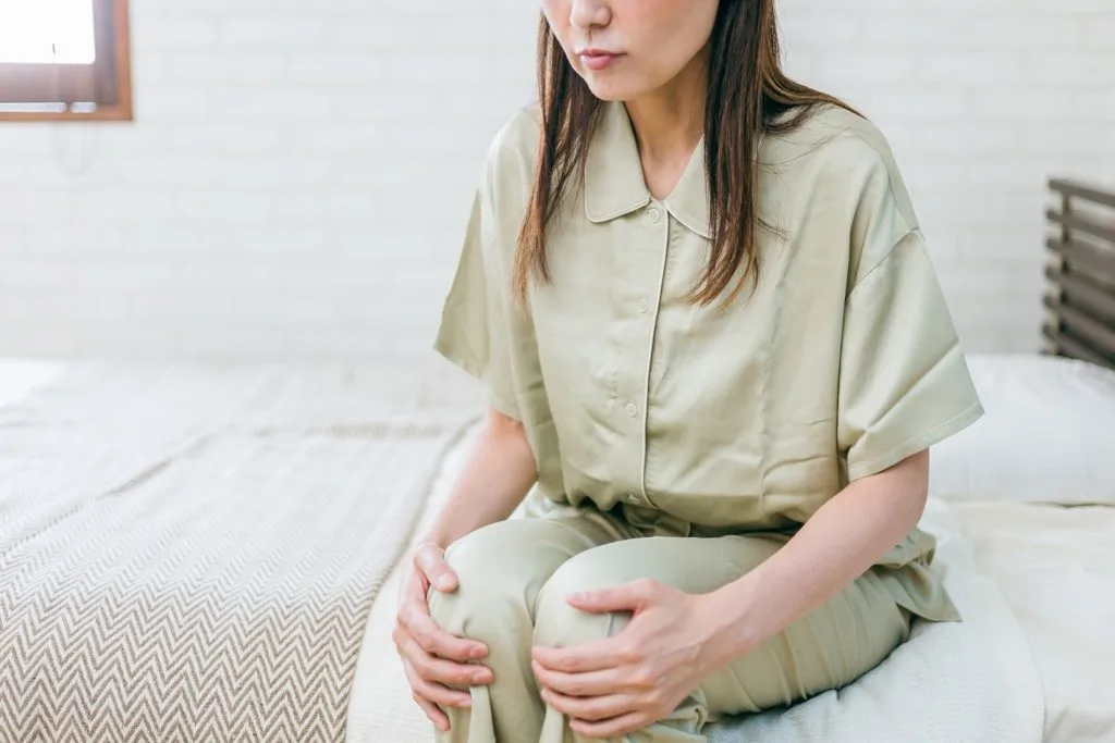 座りながら両手で膝を押さえる女性