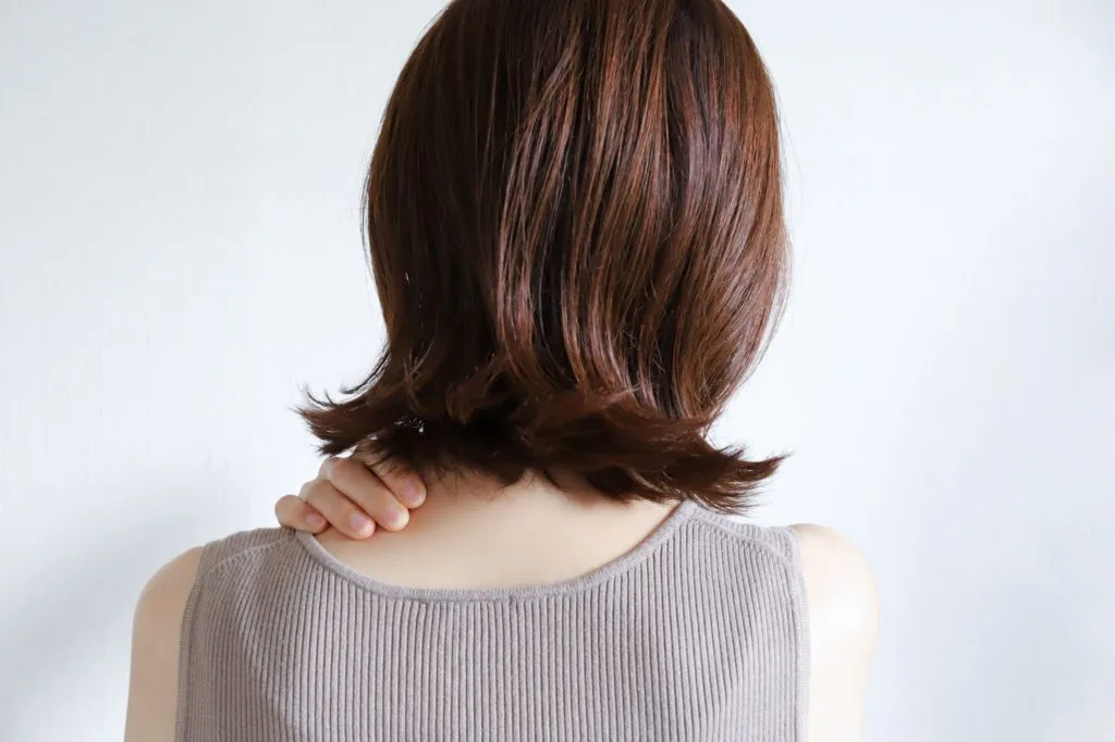右手で首の左側を押さえる女性