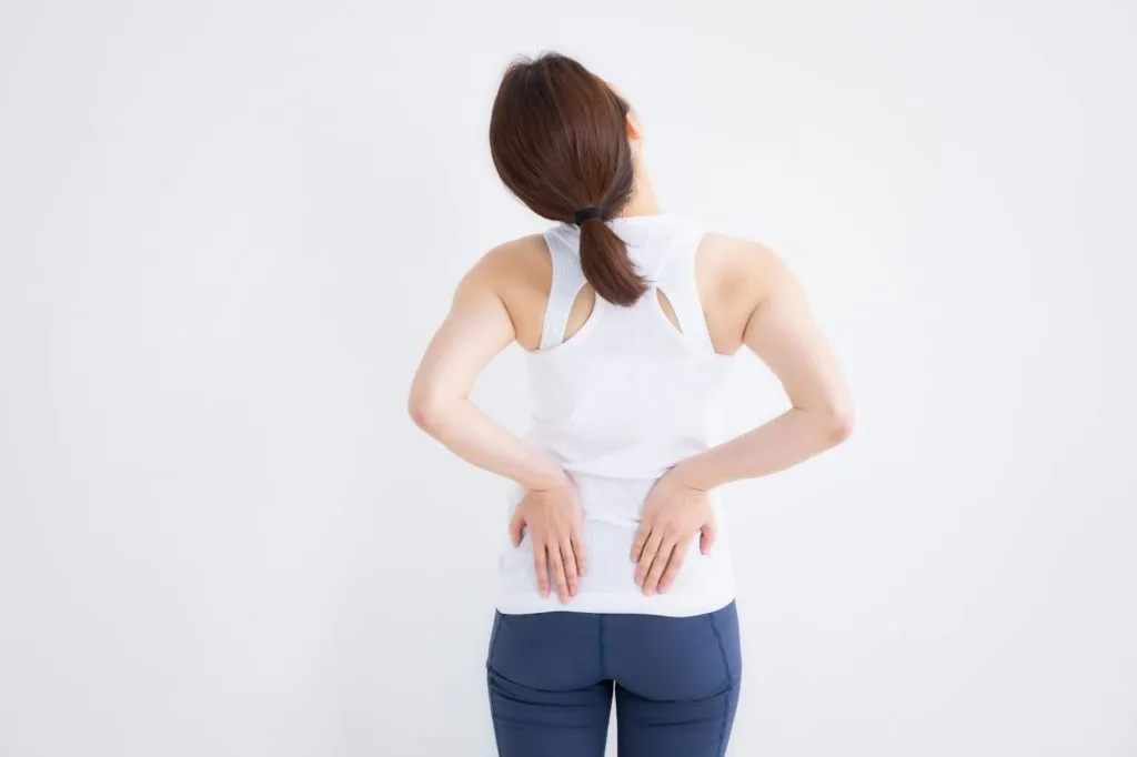 後ろ向きで両手で腰を押さえる女性