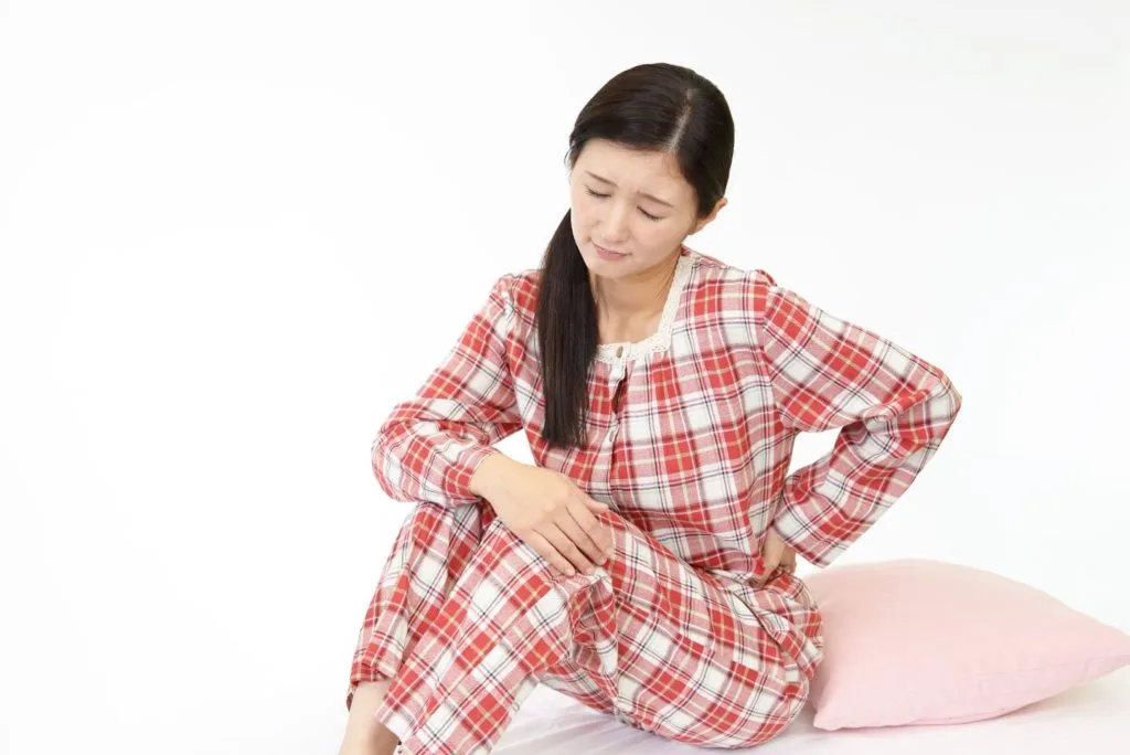 体育座りしながら腰を押さえる女性
