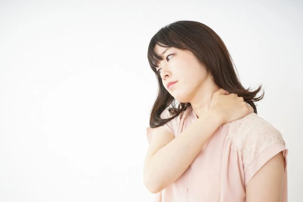 右手で首の左側を押さえる女性