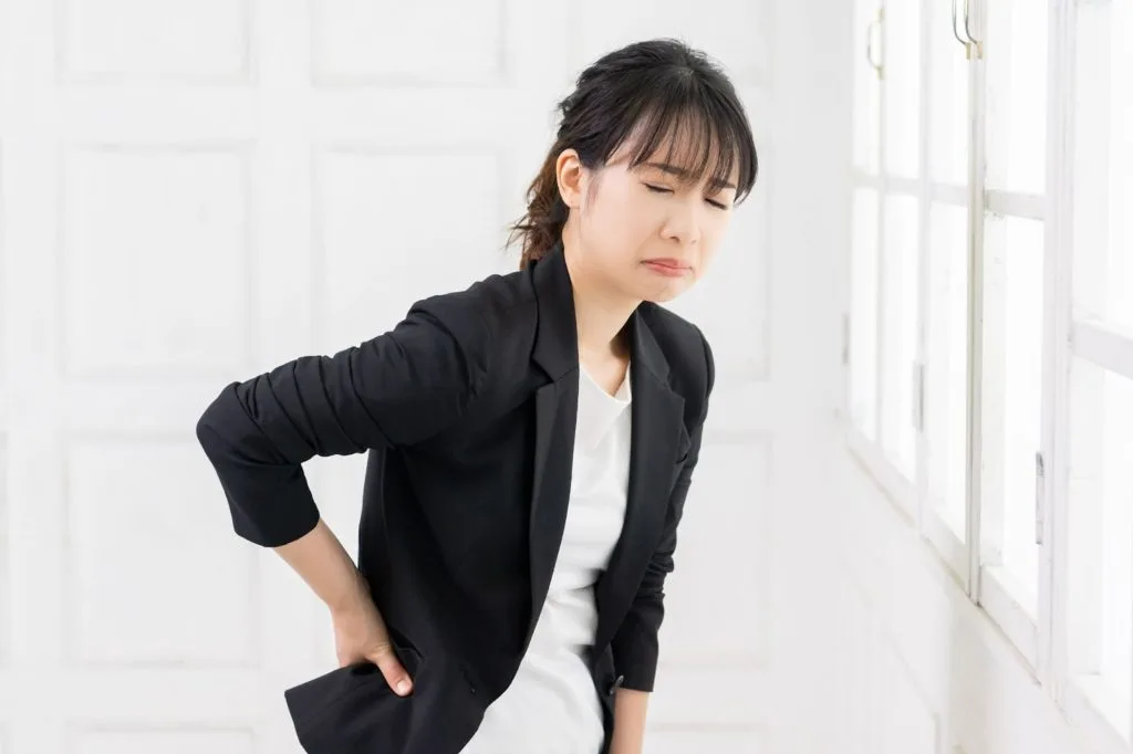 腰に手を当てて痛がる女性
