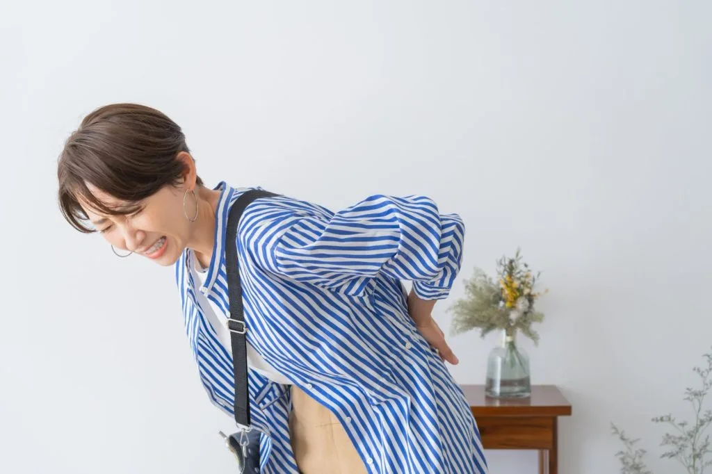 腰の痛みを気にする女性