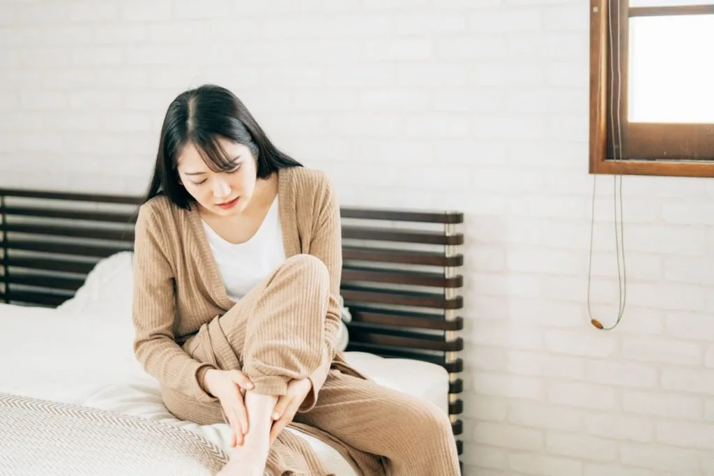 ベッドの上で足を気にする女性