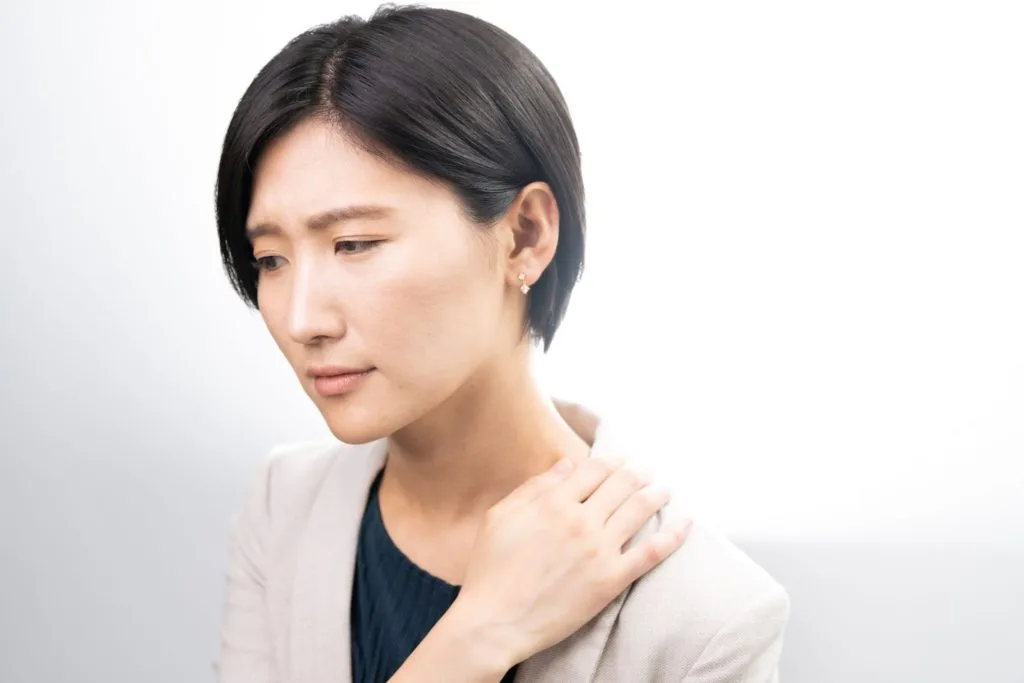 肩の辺りを気にする女性
