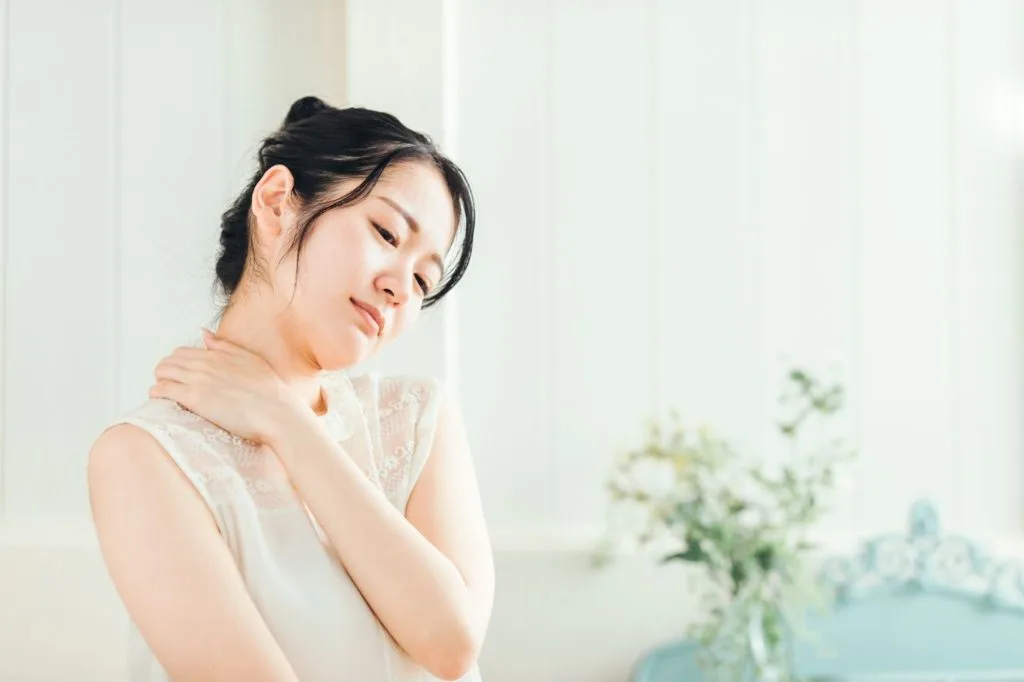 肩の辺りを気にする女性